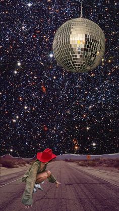 a woman in a red hat is dancing on the road with a disco ball above her head