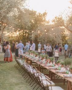 a group of people standing around a long table with plates and glasses on top of it