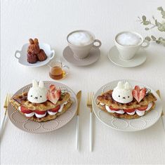 two white plates topped with food next to cups and utensils on a table