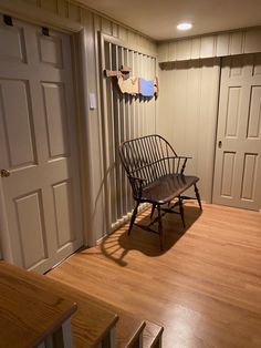 a wooden chair sitting on top of a hard wood floor next to a door and stairs