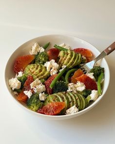 a white bowl filled with assorted vegetables and feta on top of a table