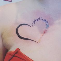 a woman's chest with a heart tattoo on her left side, and stars in the background