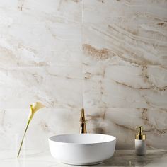 a white bowl sitting on top of a counter next to a vase with flowers in it