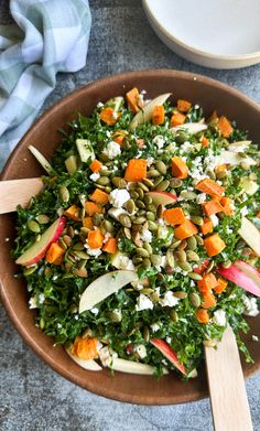 a salad with carrots, apples, and feta cheese in a wooden bowl