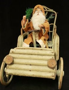 a santa clause riding in a toy car with logs on the wheels and holding a tree branch