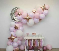 a balloon arch with pink, white and gold balloons in the shape of stars on it