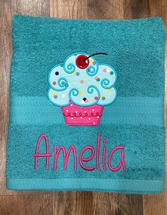 a blue towel with a cupcake on it and the word amella written in pink