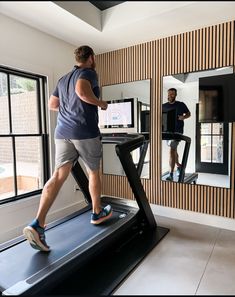 a man is running on a treadmill in front of a mirror and another man watches