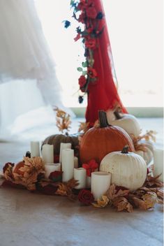 a table topped with candles and pumpkins next to a window