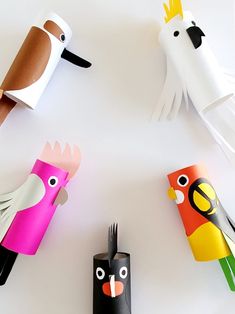 four paper birds are on the table and one is holding a fork in its mouth