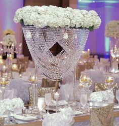 the table is set with white flowers and crystal vases for centerpieces on it