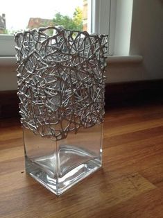 a glass vase sitting on top of a wooden floor next to a window sill