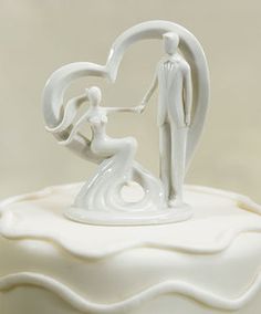 a wedding cake topper with a bride and groom kissing on the beach in white frosting