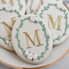 decorated cookies with the letter m on them sitting on top of a white and gold plate