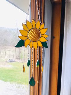 a sunflower wind chime hanging from the side of a window with green tears