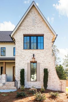 a white brick house with black shutters on the front door and stairs leading up to it