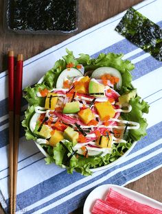 a salad on a plate with chopsticks next to it