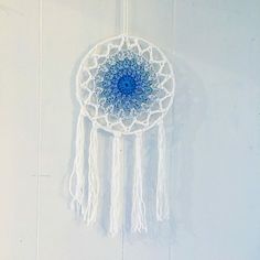 a blue and white dream catcher hanging on the wall