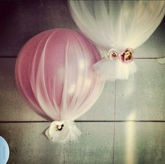 two balloons with white tulle and pink flowers on the top one has a large balloon attached to it's side