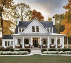 a large white house with black roof and columns on the front porch, surrounded by trees