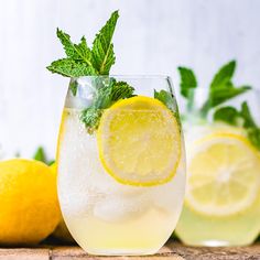 a glass filled with lemonade spritz next to sliced lemons and mint