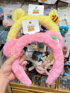 a person holding a pink stuffed animal in front of a store shelf with toys on it