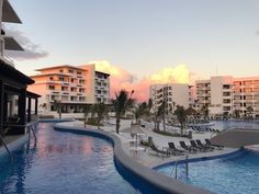 an outdoor swimming pool with lounge chairs and palm trees in the background at sunset or dawn