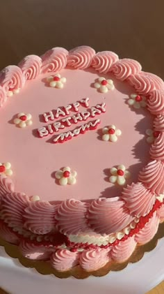 a pink birthday cake with white and red decorations