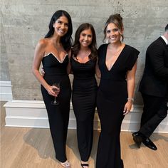 three beautiful women standing next to each other in front of a wall with wine glasses