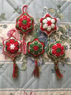 four red and green ornaments are on a blue tablecloth with white trimmings