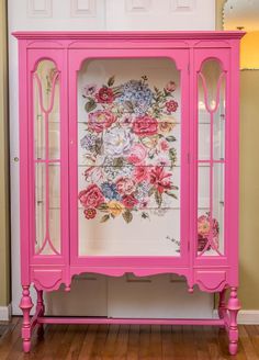 a pink china cabinet with flowers painted on it