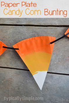 paper plate candy corn bunting on a wooden table with text overlay that reads, paper plate candy corn bunting