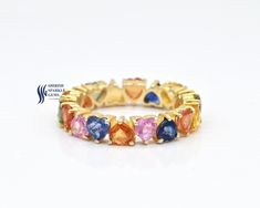 a yellow gold ring with multi colored stones