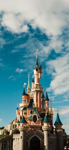 the castle has many turrets and towers on it's sides, with blue sky in the background