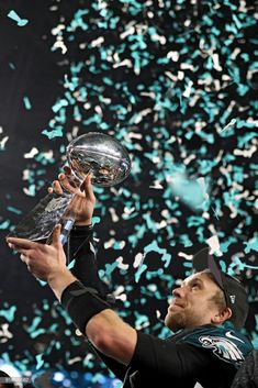 a man holding up a trophy in front of confetti