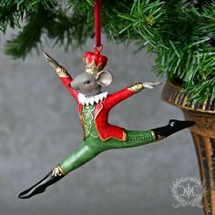 a christmas ornament hanging from a tree with a mouse on it's back