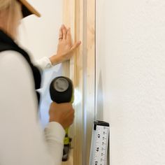 a woman is measuring the wall with a tape measure and an angle ruler in front of her