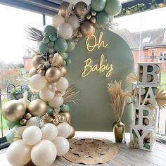 an arch made out of balloons with the words oh baby on it and palm leaves