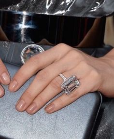 a close up of a person's hand with two rings on top of a suitcase