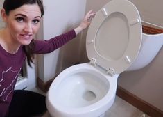 a woman is holding the lid on a toilet