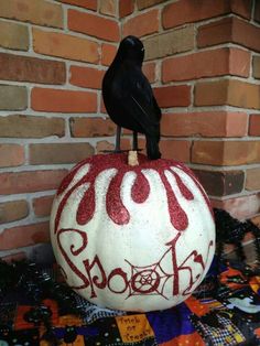 a black bird is sitting on top of a pumpkin that has been painted red and white