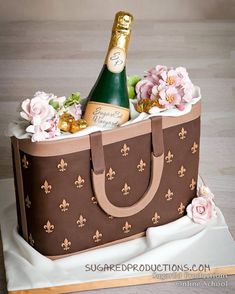 a book with a cake in the shape of a bag and flowers on it, including a bottle of champagne