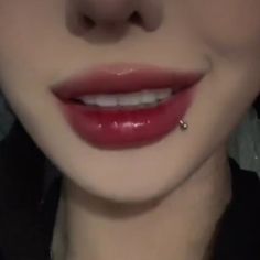 a close up shot of a woman's face with red lipstick and piercing on her nose