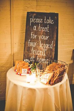 a table with a sign that says please take a treat for your four legged friend at dinner