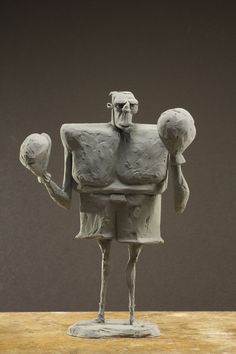 a sculpture of a man holding two balls in one hand and an object in the other