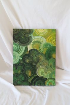 an abstract painting with green and yellow swirls on a white sheeted bed spread