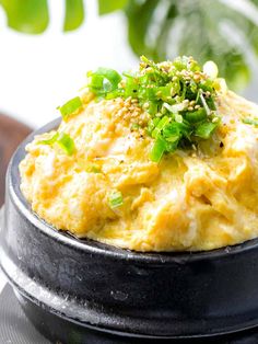 an omelet is sitting on a plate with green onions and seasoning sprinkles