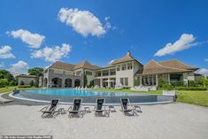 a large house with a pool and lawn chairs