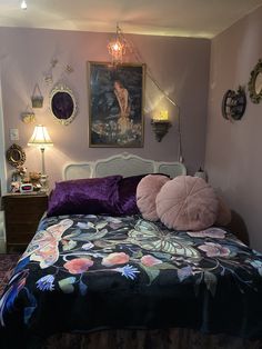 a bed with purple and black comforter in a bedroom next to a painting on the wall