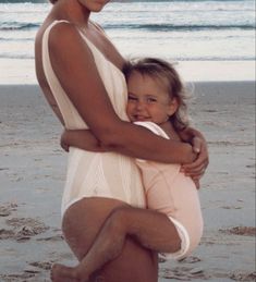 a woman holding a child on the beach